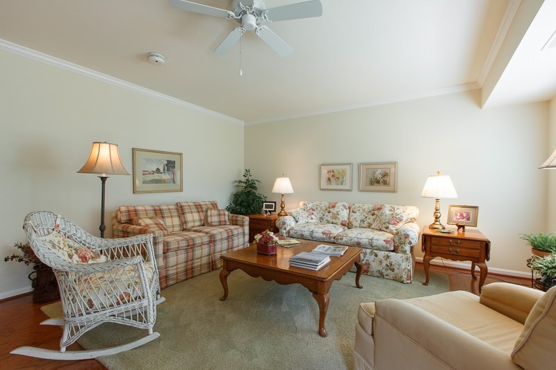 A cozy living room featuring traditional-style furniture, including sofas and a wooden coffee table, illuminated by lamps.