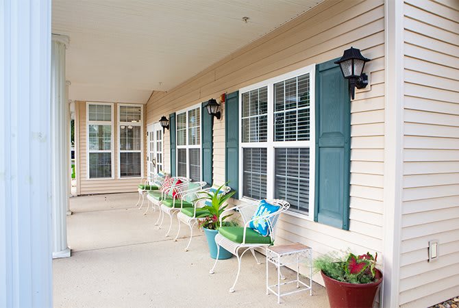 A cozy porch with colorful chairs and potted plants.