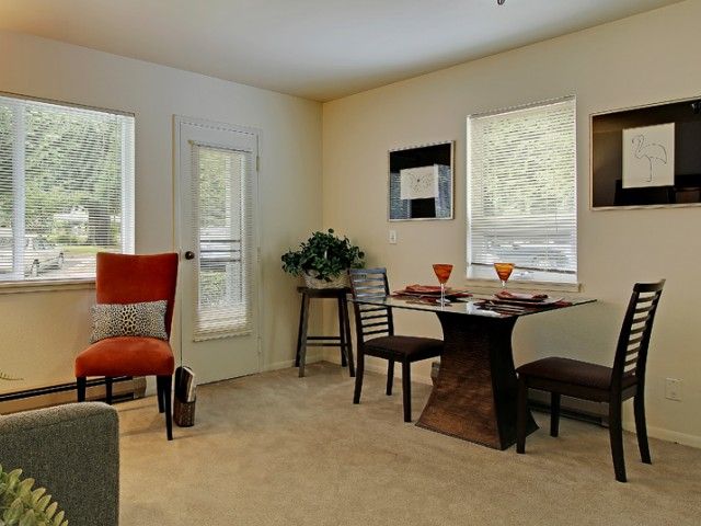 A cozy dining area with a table set for two, featuring modern decor and natural lighting.