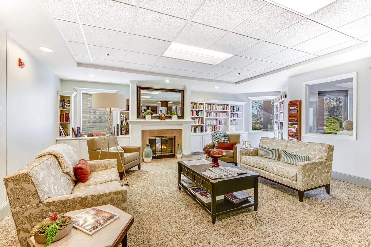 A cozy living room with comfortable sofas and a coffee table, surrounded by bookshelves and decorative elements.