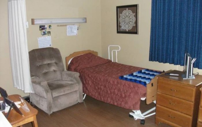 A hospital room with a bed, chair, and curtains.