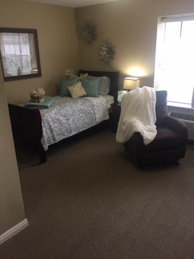 A cozy bedroom with a bed, armchair, and soft lighting.