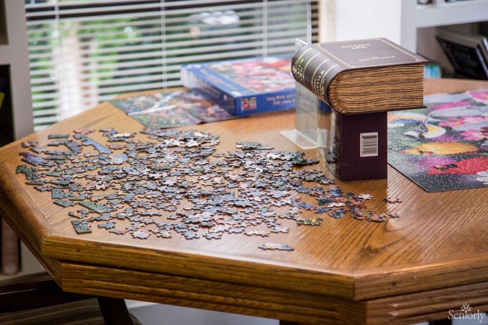 A table with scattered jigsaw puzzle pieces next to books.