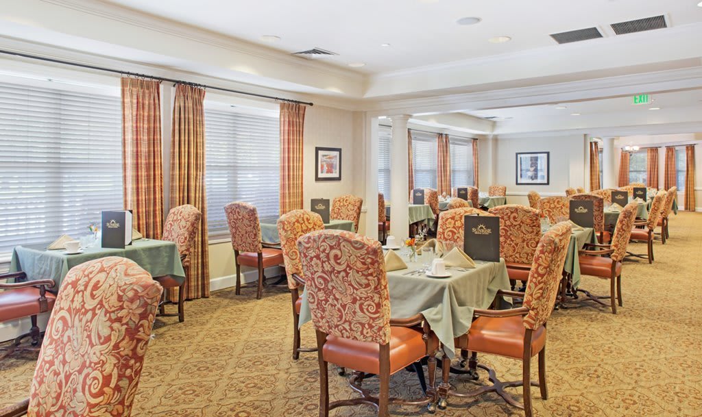 A well-appointed dining room with elegantly set tables and upholstered chairs.