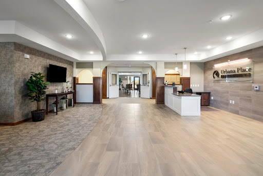A spacious and modern lobby area featuring a reception desk, kitchenette, and contemporary lighting.
