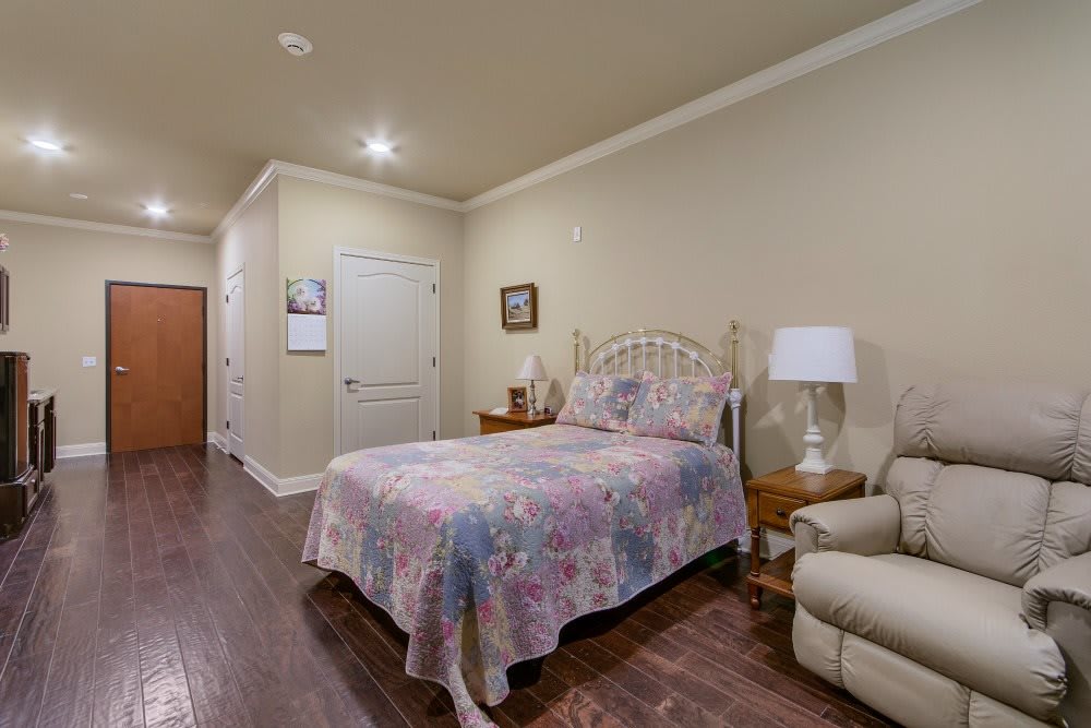 A cozy bedroom with a floral bedspread, wooden floors, and comfortable seating.