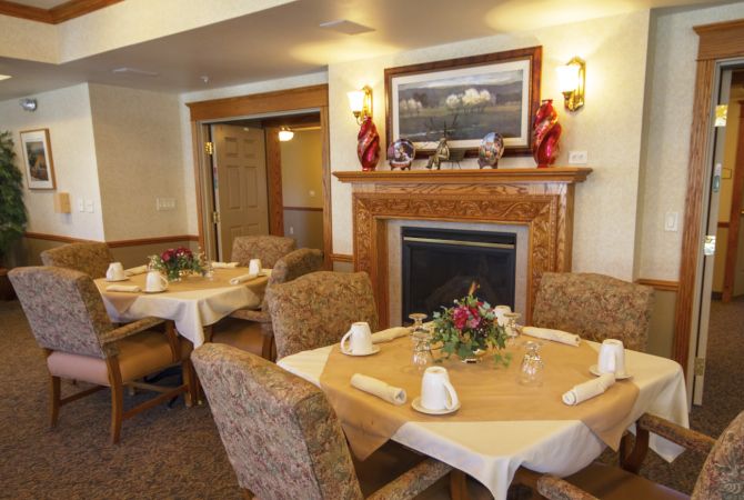 A cozy dining room with elegantly set tables and a decorative fireplace.