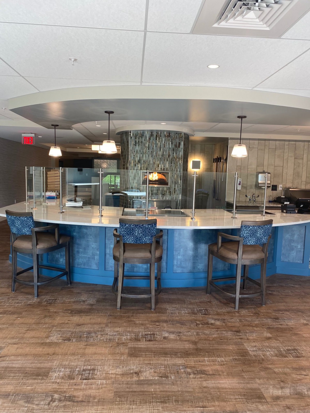 A modern bar area with a curved counter, stylish chairs, and elegant lighting fixtures.