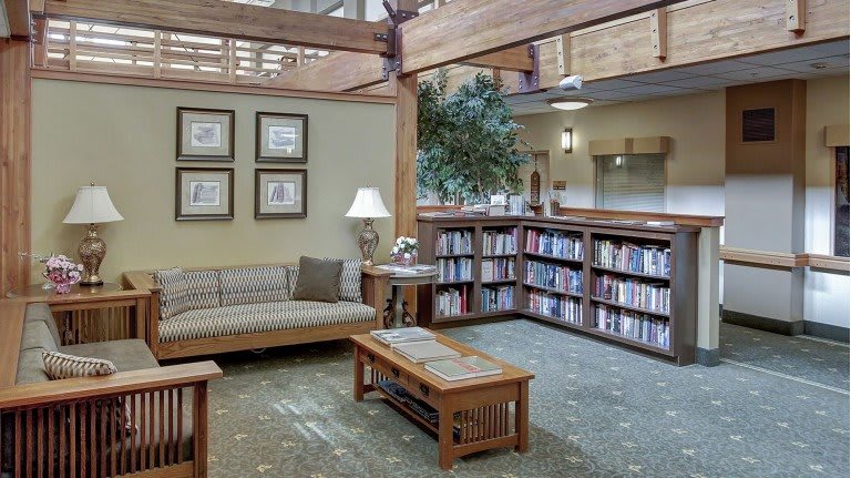 A cozy library corner with a sofa, bookshelves, and warm lighting.