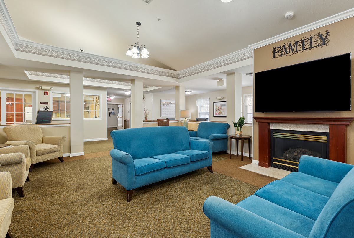 A cozy living room with blue sofas, a fireplace, and a large television.