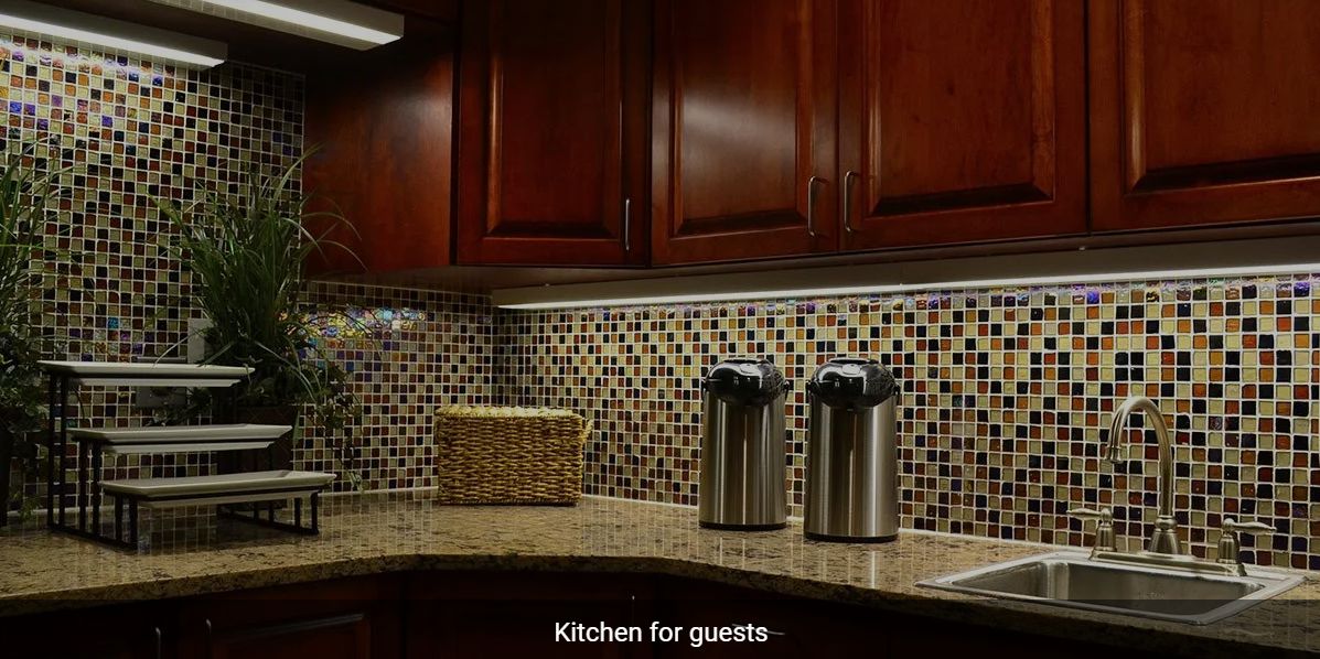 A kitchen with mosaic backsplash and stainless steel thermoses on the counter.