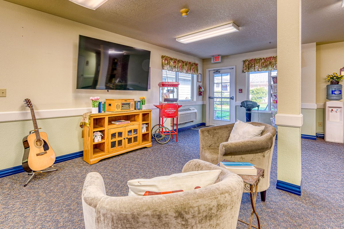 A cozy waiting area with comfortable chairs, a large television, and a popcorn machine by the window.
