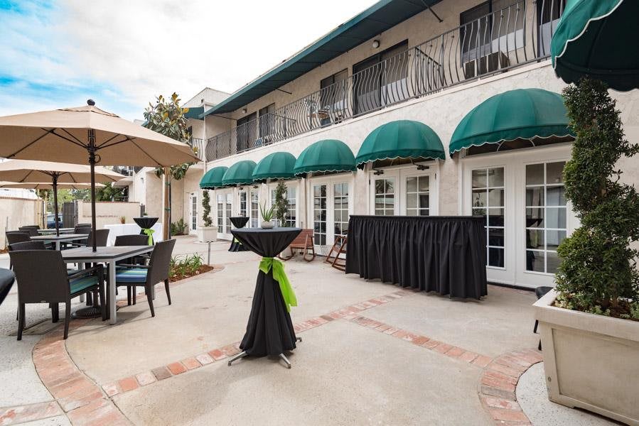 An outdoor courtyard setup for an event with tables and green awnings.