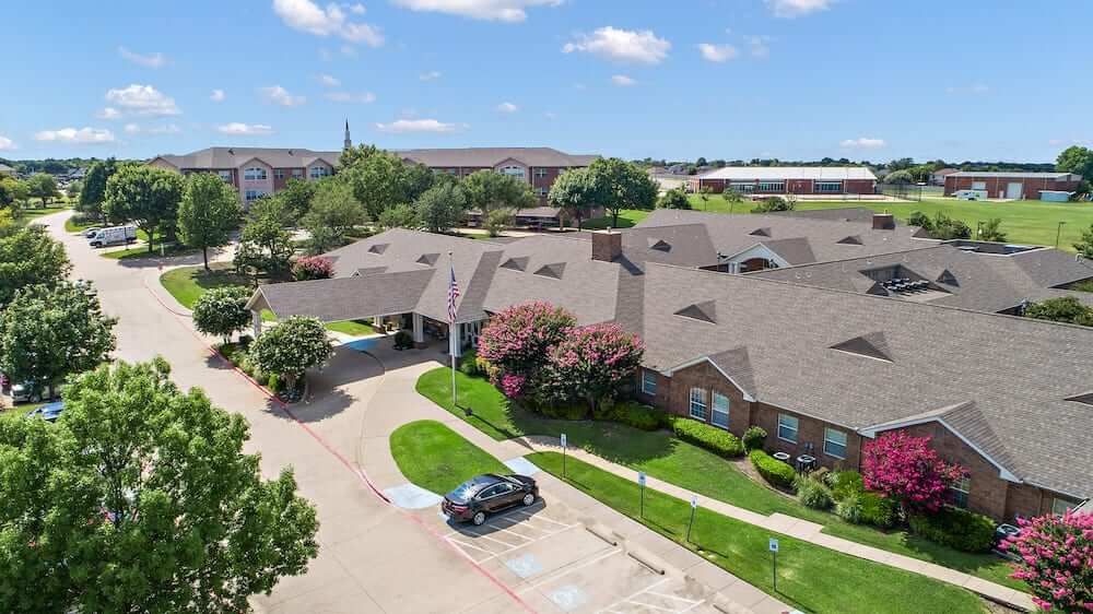 Aerial view of a residential building with a parking lot and landscaped surroundings.