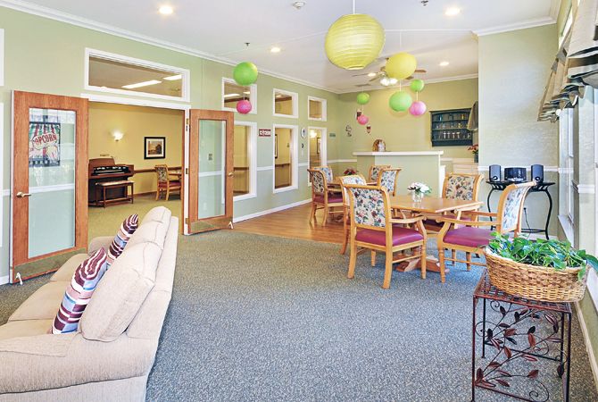 A brightly decorated community living space with tables, chairs, and colorful balloons.