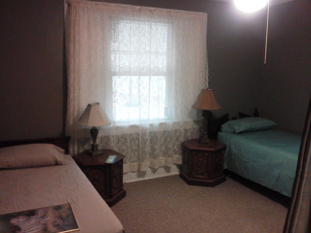 A cozy bedroom with two beds and a window adorned with curtains.