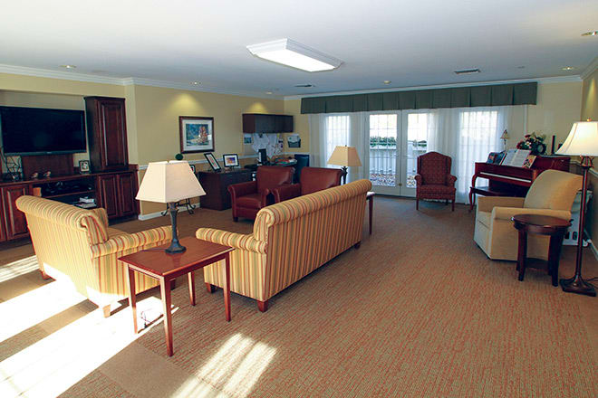 A spacious and well-furnished living room with sofas, lamps, and large windows.