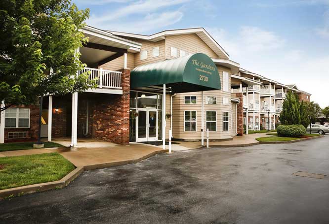 The exterior of a residential apartment building with an entrance featuring a green awning.