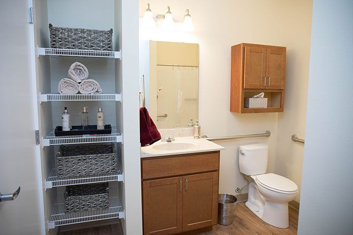 A neatly organized bathroom with shelves, a sink, mirror, and wooden cabinets.