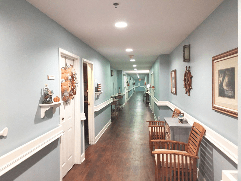 A well-lit hallway with wooden chairs and decorative elements on the walls.