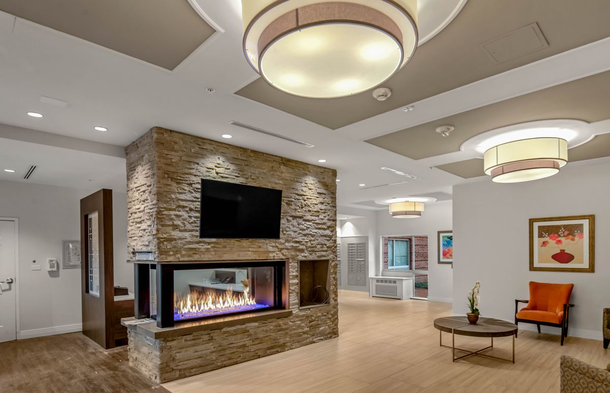 A modern living room interior featuring a stylish stone fireplace, contemporary lighting, and sleek furnishings.