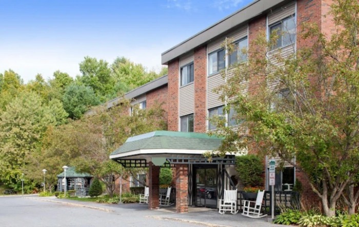 A hotel entrance with an awning and surrounding trees.