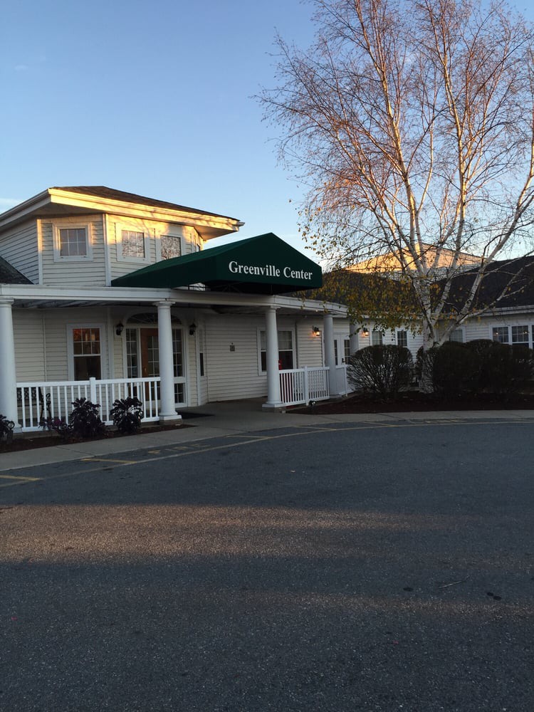 Entrance of a building with an awning surrounded by trees at sunset.