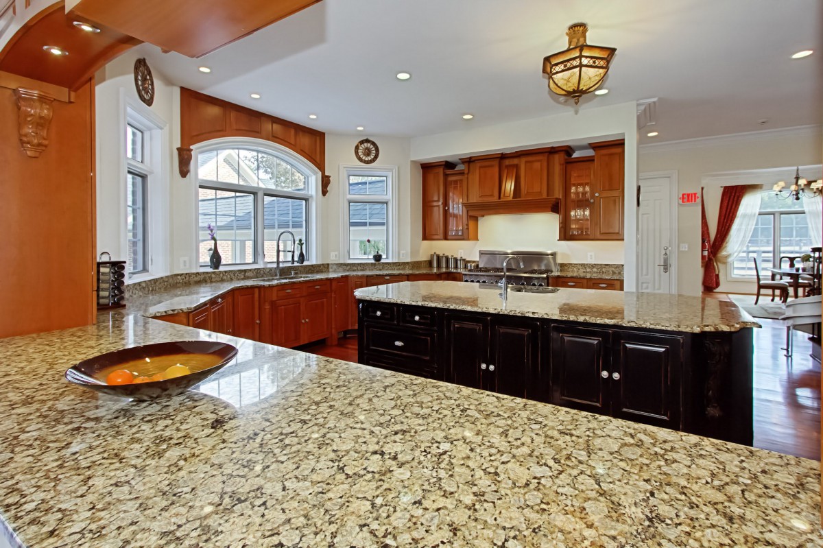 A modern kitchen with granite countertops and a central island.