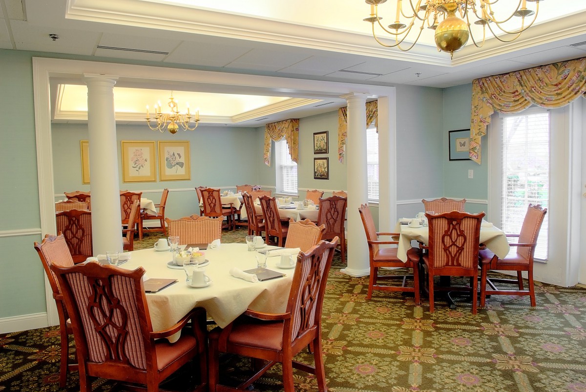 A traditional dining room with elegantly set tables and chandeliers.