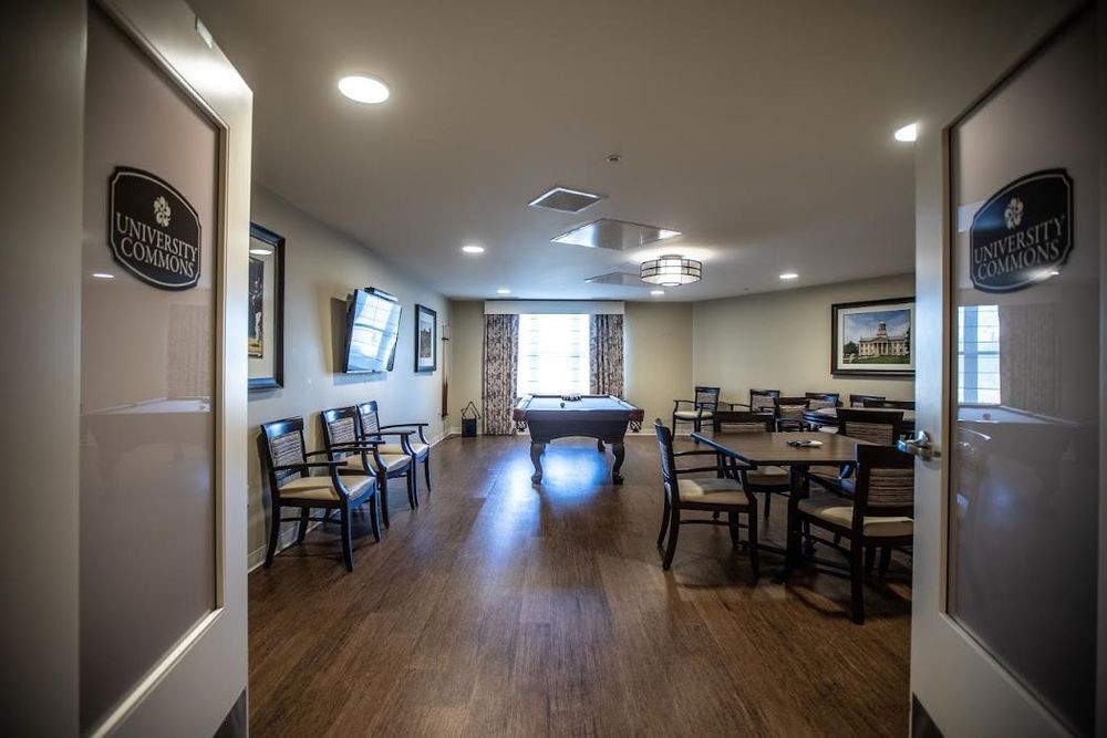 A well-furnished room featuring tables, chairs, a pool table, and a television.