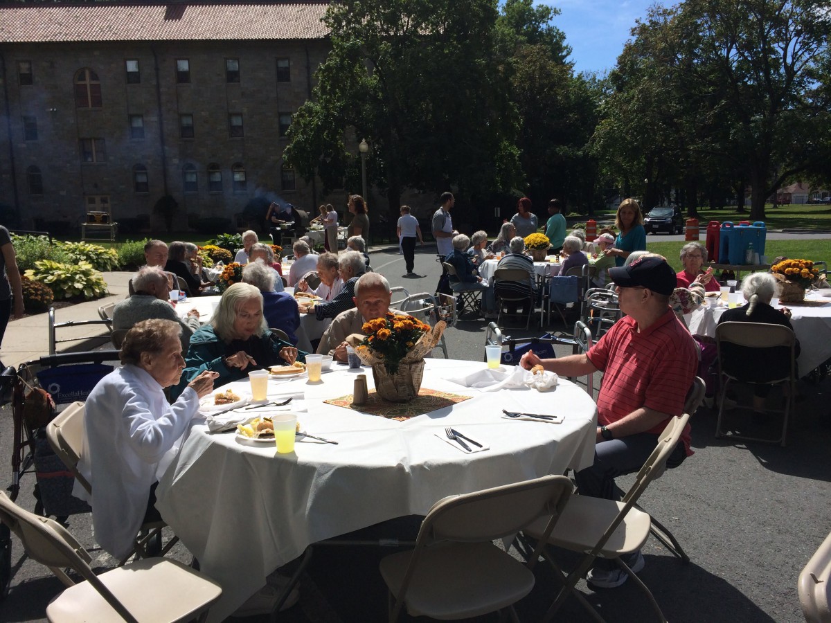 A group of people enjoying an outdoor gathering on a sunny day, seated around tables.