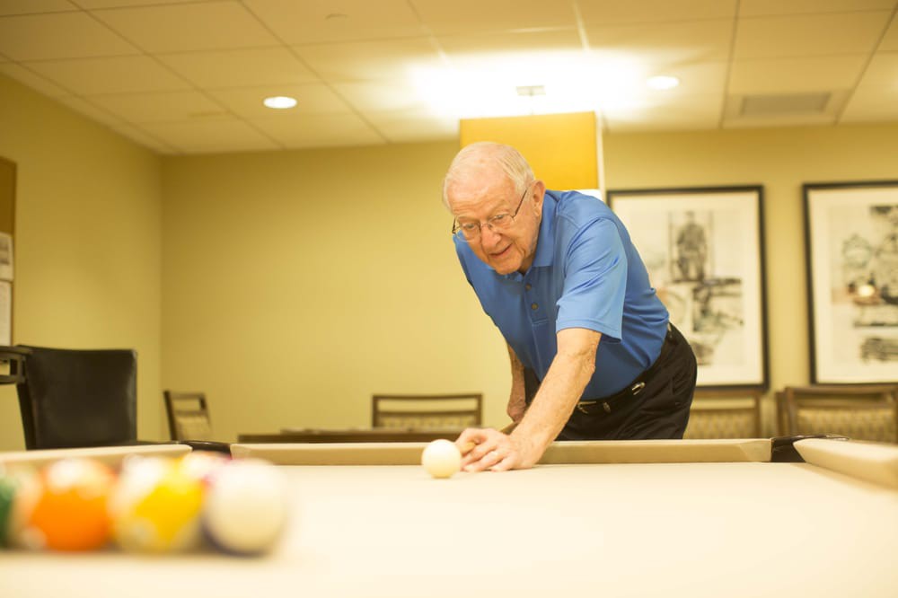 A person in a blue shirt playing billiards on an indoor pool table.