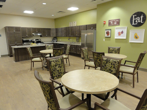 A modern kitchen and dining area featuring wooden tables and stylish chairs, set against a vibrant green wall.