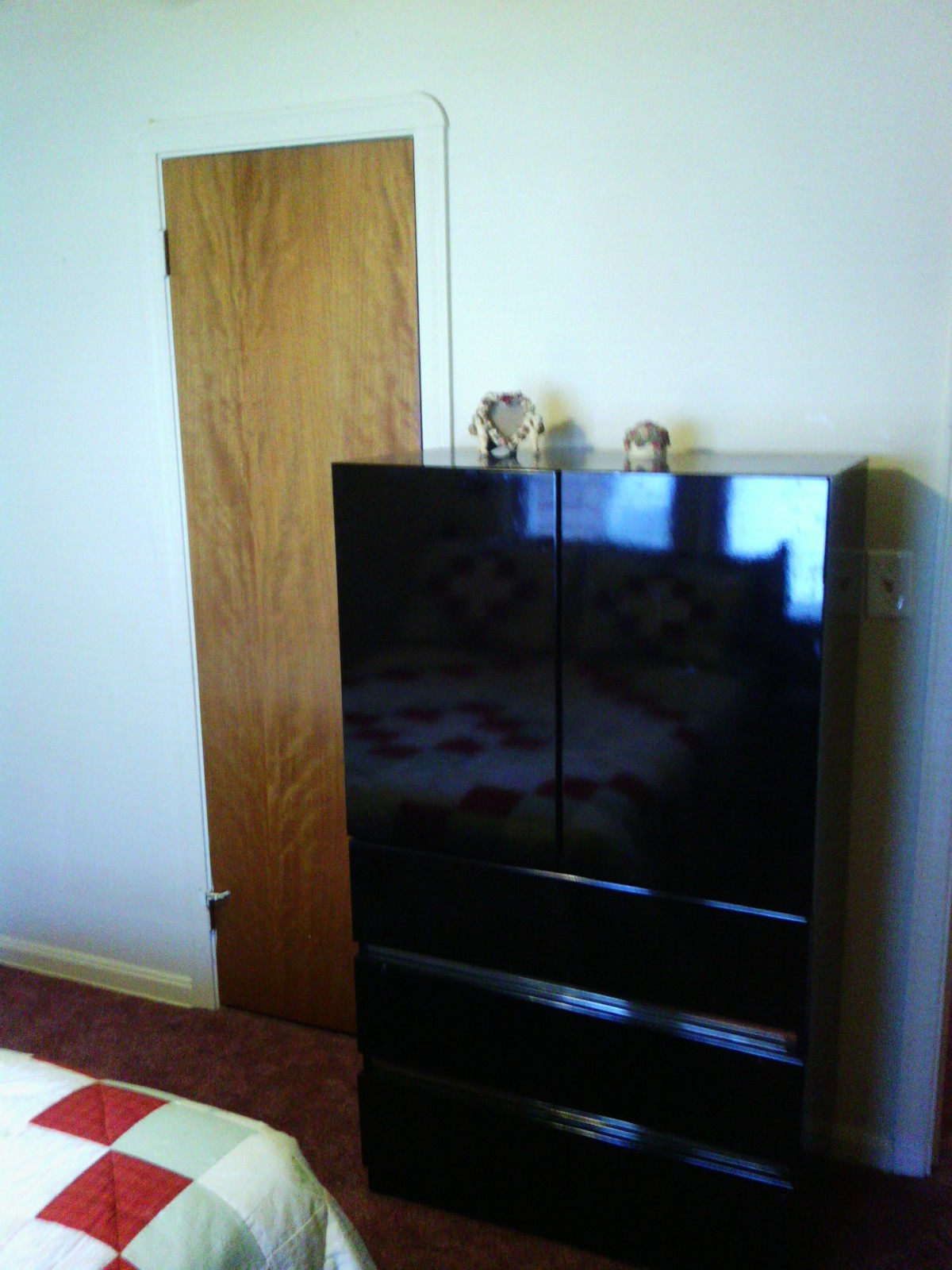 A bedroom with a black cabinet and a wooden door.