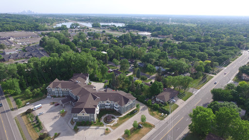 An aerial view showcasing a lush residential area with homes nestled among trees and a nearby road.