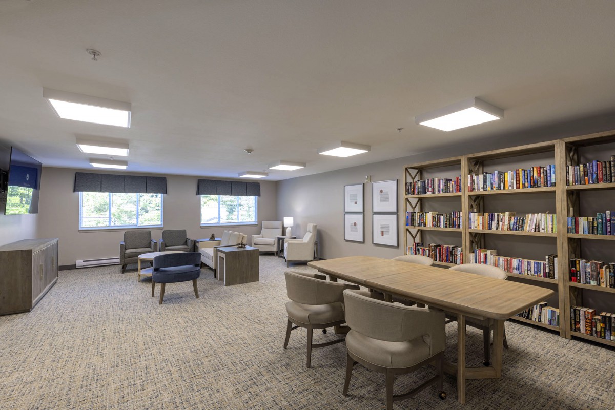 A modern library reading room with bookshelves, tables, and comfortable seating.