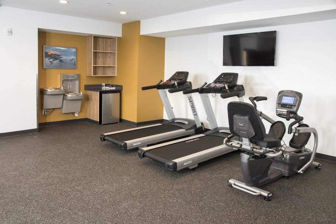 A modern gym with treadmills, exercise bikes, and a television for entertainment.