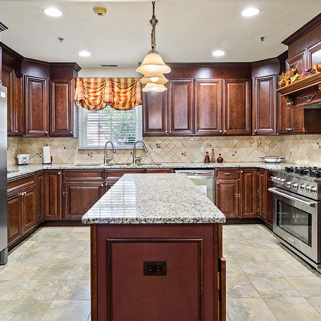 A spacious kitchen with wooden cabinets and granite countertops featuring a central island.