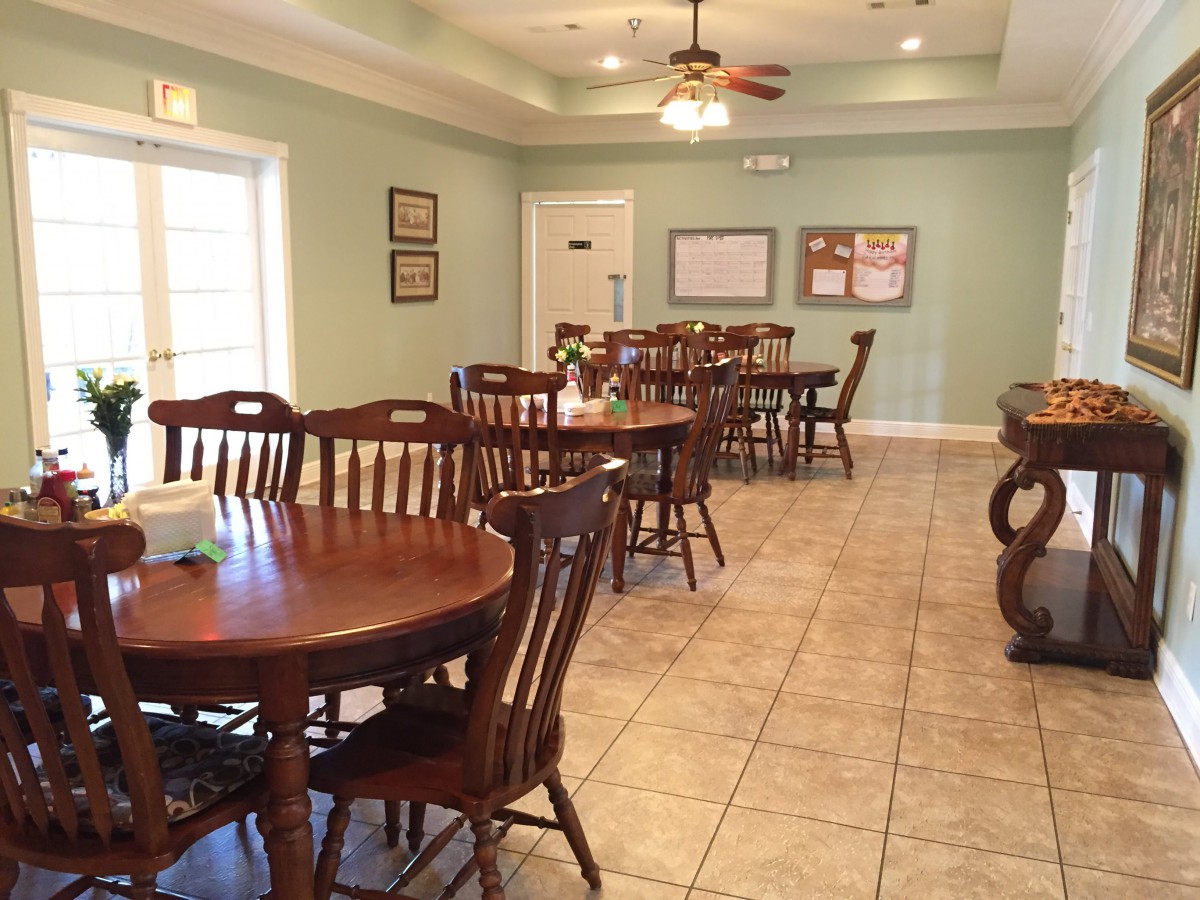 A cozy dining room with multiple tables and chairs, featuring a ceiling fan and tiled flooring.