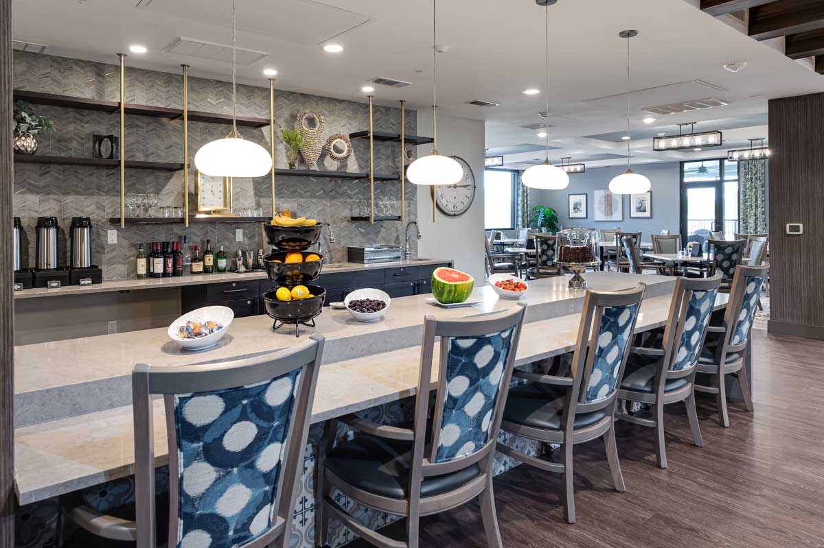 A modern kitchen with bar stools and elegant lighting.