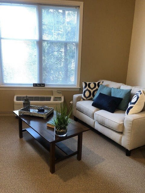 A cozy living room with a white couch, colorful pillows, and a wooden coffee table.