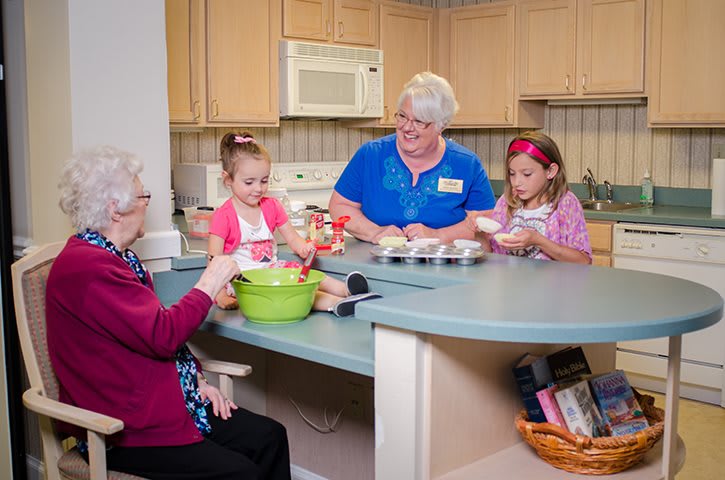 A group of people, including two children and an elderly person, engaged in a baking activity in the kitchen.