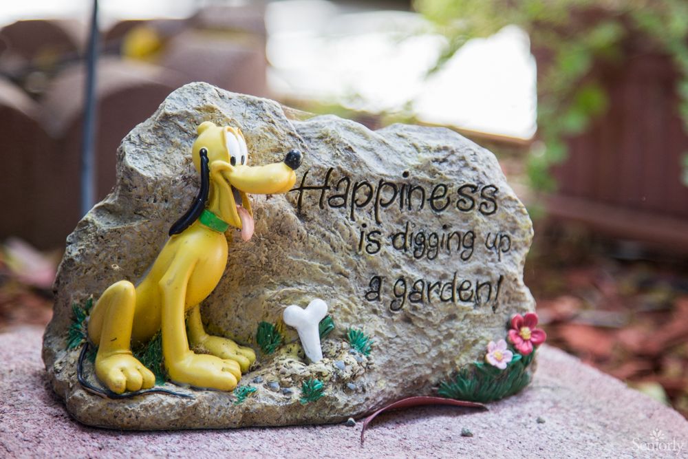 Decorative garden stone with a dog figure and 'Happiness is digging up a garden!' quote.