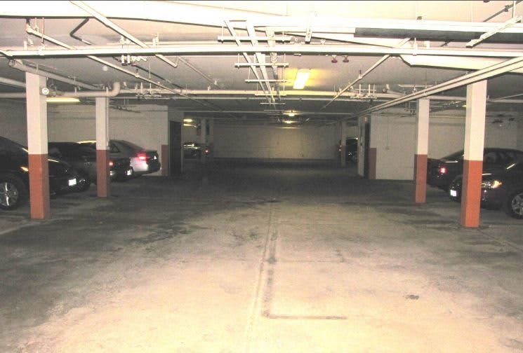 An underground parking garage with dim lighting and parked cars.