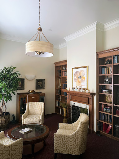 A cozy reading nook featuring comfortable chairs, bookshelves filled with books, and a decorative plant.