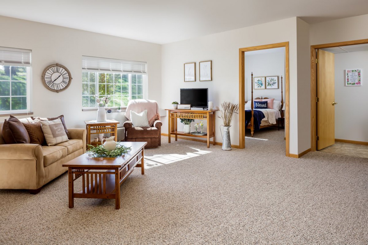 A bright and cozy living room with comfortable furniture and a view into the bedroom.