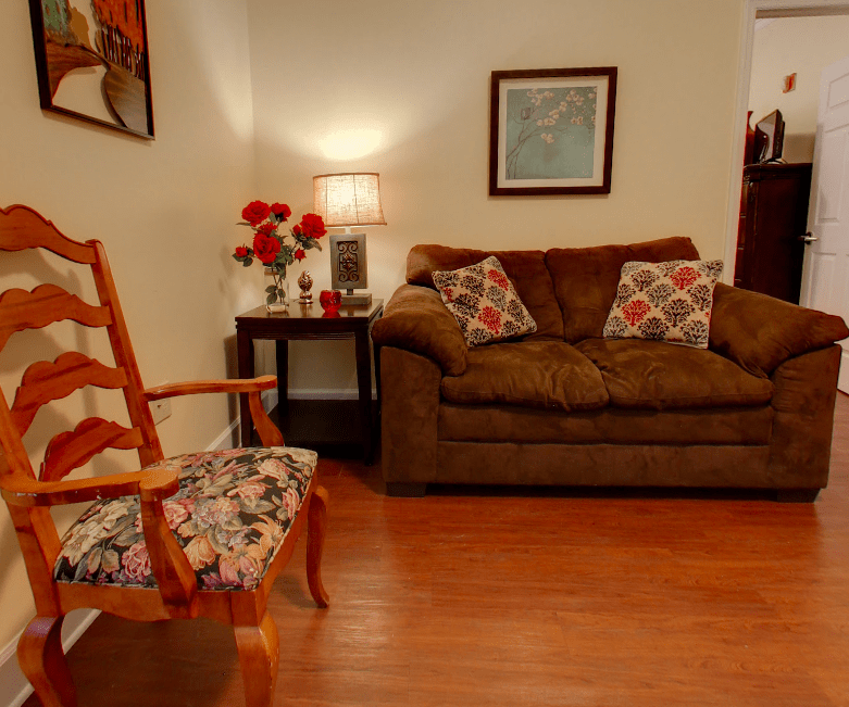 A cozy living room with a sofa, armchair, and warm lighting.