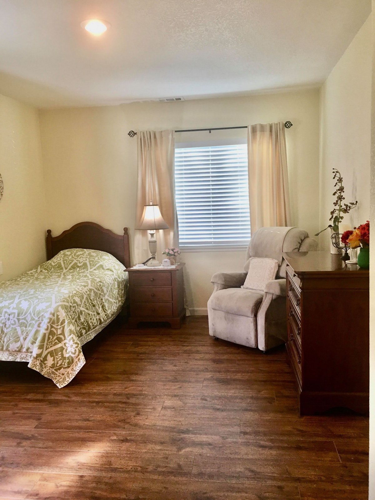 Cozy bedroom with a single bed, nightstand lamp, and comfortable seating.