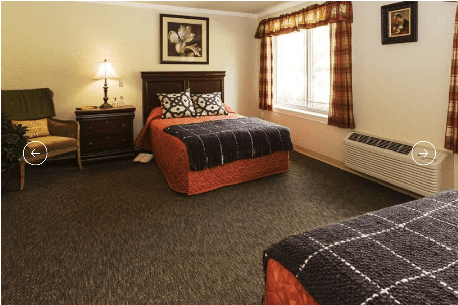 A cozy hotel room with two double beds, a nightstand, and a large window.
