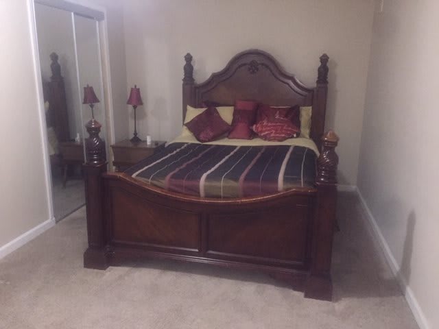 A bedroom featuring a classic wooden bed with decorative pillows.